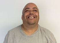 Power Staff Joe Chandler, a smiling bald person wearing a gray T shirt